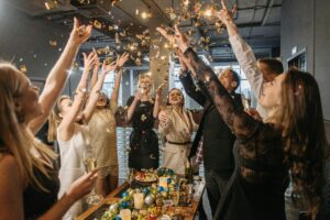 A lively gathering of adults celebrating indoors with confetti and champagne.