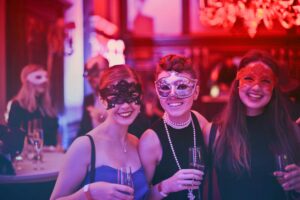 A vibrant masquerade party with happy guests wearing decorative masks and holding champagne glasses.